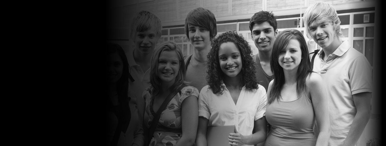 young happy students standing in front of brick wall 